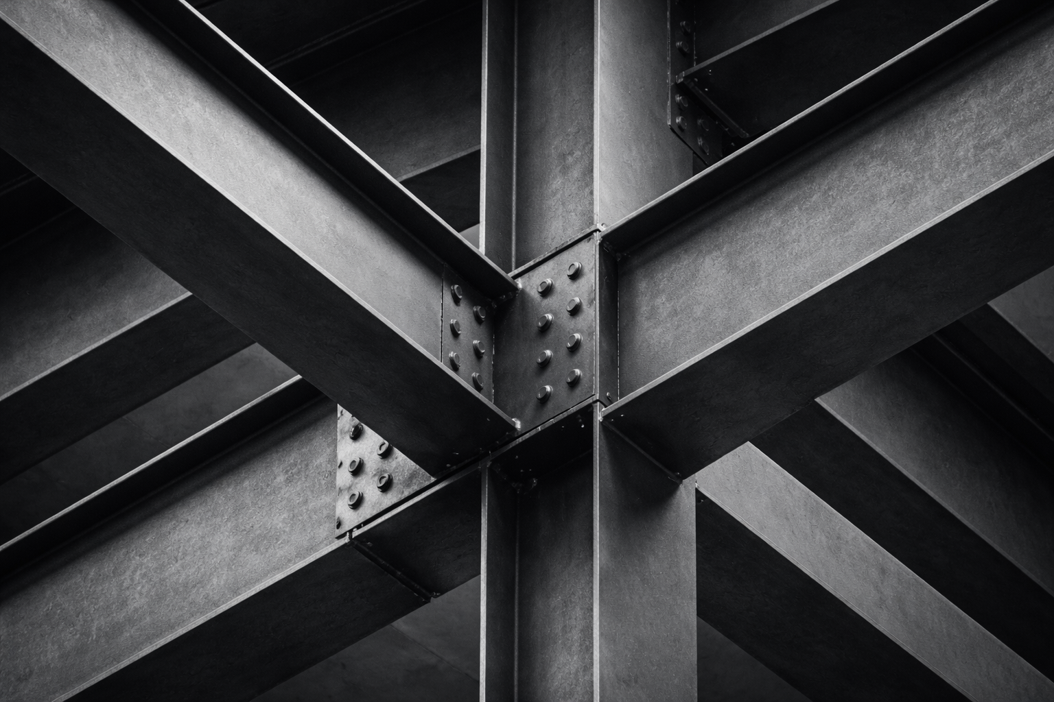 Abstract close-up of intersecting steel beams illustrating commercial intelligence as decision infrastructure that supports coordinated B2B growth.