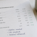 Printed marketing report showing vanity metrics crossed out and revenue metrics written in